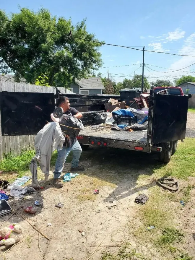 Crew members loading debris into a trailer during a job site cleanup.