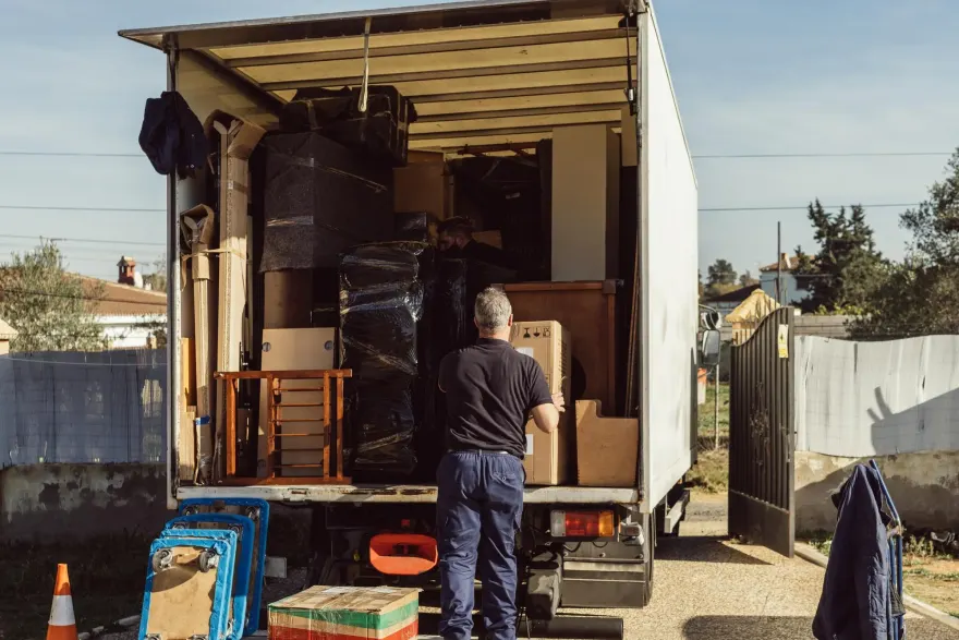 A Cowboys Hauling crew member loading furniture into the back of a moving truck.